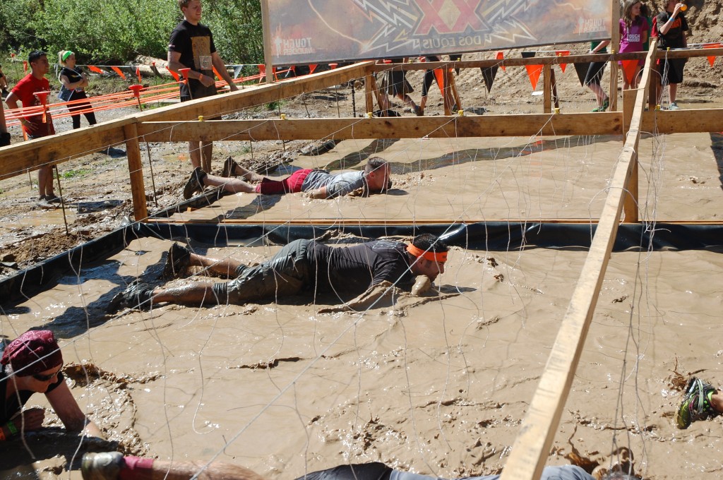 Steve Kopff, a two-year participant of the Tough Mudder in Beaver Creek, Colorado, moves through a watered-down muddy pit while dealing with electrical wires in the Electric Eel obstacle