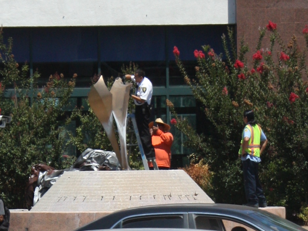 City of Cerritos employees examine the "Dancer" art sculpture that was "beheaded" by robbers early Saturday morning. Randy Economy Photo