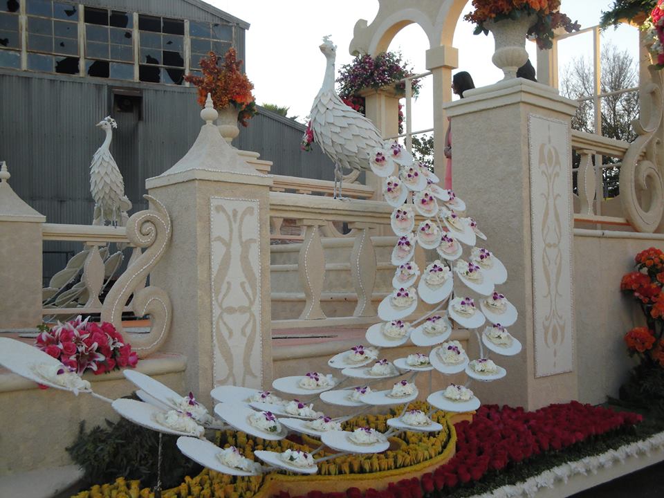 Downey Rose Parade Float features intricate details including a flowered white peacock.